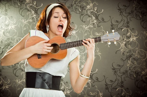 Vintage mulher joga ukulele e cantar em fundo de tapeçaria — Fotografia de Stock