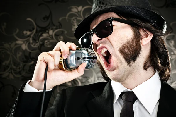Elegantní šéf sluneční brýle a mikrofon zpěv portrét na černém pozadí — Stock fotografie