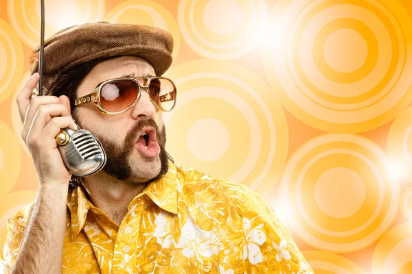1970 vintage show man cantar com camisa havaiana e microfone no fundo amarelo — Fotografia de Stock