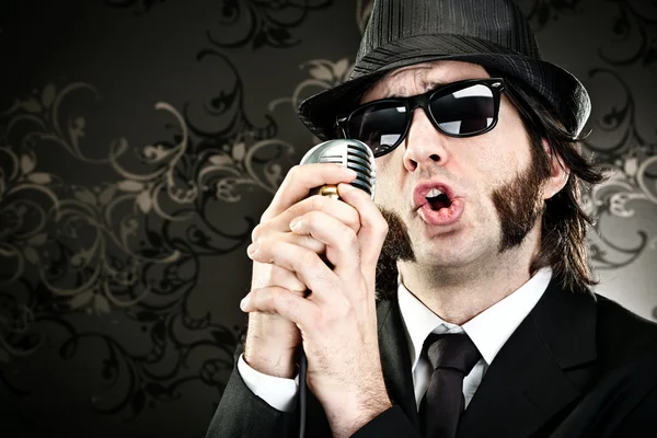 Elegant boss man with sunglasses and microphone singing portrait on black background — Stock Photo, Image