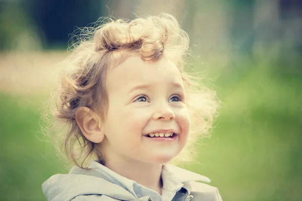 Beautiful blond curly hair child play outdoor in a park — Stock Photo, Image