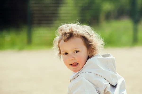 Prachtig blond krullend haar kind spelen buiten in een park — Stockfoto