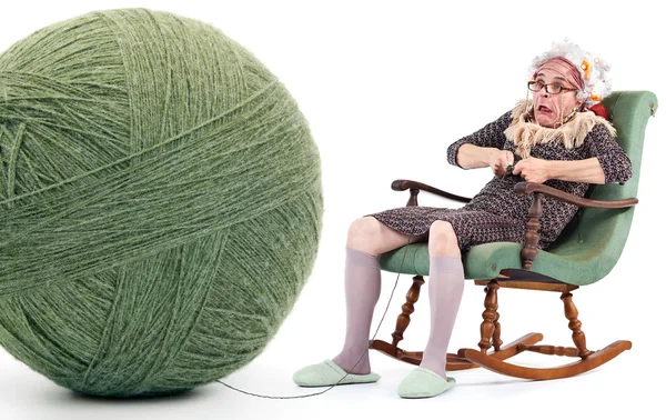 Lustige alte Dame strickt mit riesigem Garnknäuel isoliert auf weiß — Stockfoto