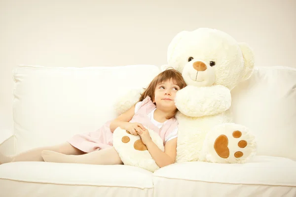 Bionda femmina bambino giocare con il suo orsacchiotto bianco in un letto — Foto Stock