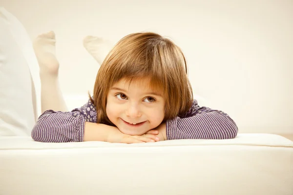 Rubia niña jugando con su osito de peluche blanco en una cama — Foto de Stock