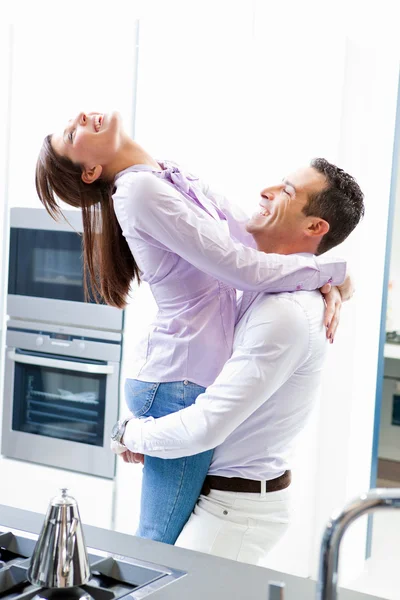 Young happy couple in love hug in home kitchen — Stock Photo, Image