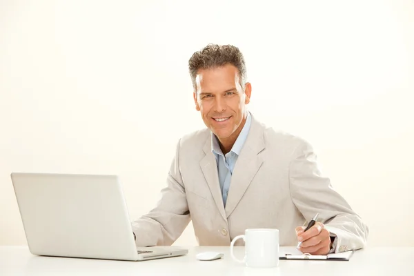 Bell'uomo d'affari sorridente lavora con computer portatile isolato su bianco — Foto Stock