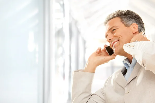 Красивый улыбающийся бизнесмен разговаривает по телефону в офисе — стоковое фото