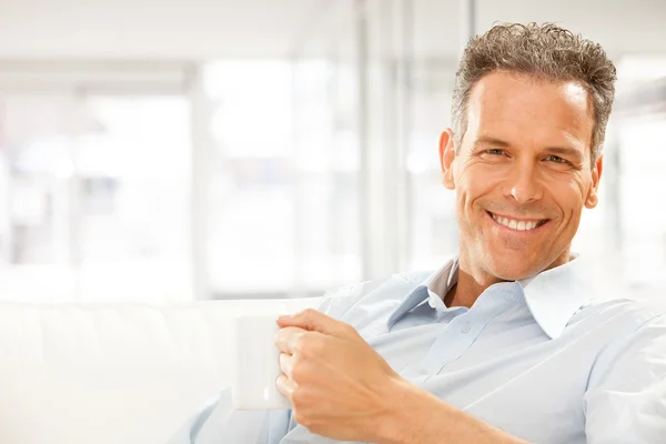 Guapo sonriente empresario beber taza de té en la oficina — Foto de Stock