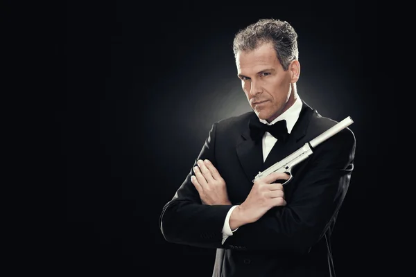 Elegant man with bow tie and gun isolated on black — Stock Photo, Image