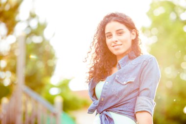 Gün batımında güzel kıvırcık kız bir Bahçe 