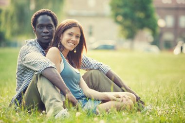 young multi-ethnic couple having fun together at the park clipart