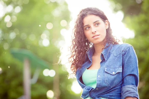 Beautiful curly girl at sunset in a garden — Stock Photo, Image