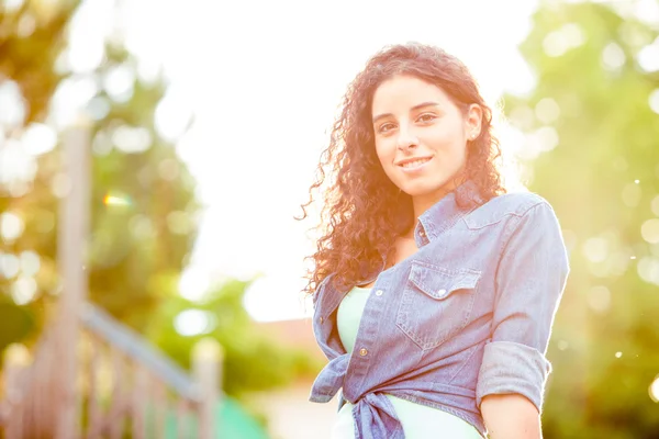 Beautiful curly girl at sunset in a garden — Stock Photo, Image
