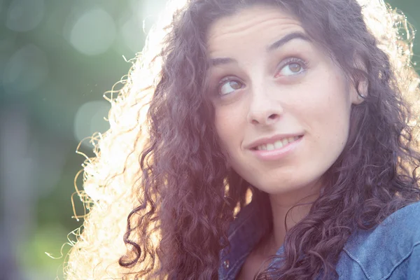 Mooi krullend meisje portret bij zonsondergang in een tuin — Stockfoto