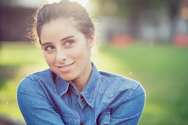 Mooi krullend meisje portret bij zonsondergang in een tuin — Stockfoto