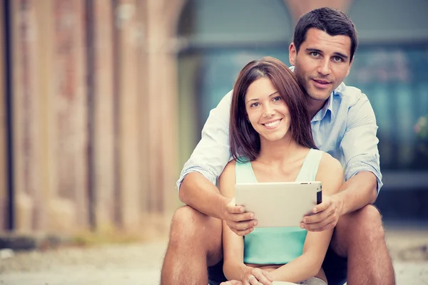 Young brunette couple having fun together with tablet at park — Stock Photo, Image