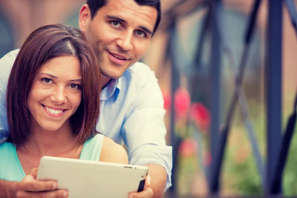 Joven morena pareja divirtiéndose junto con tableta en parque — Foto de Stock