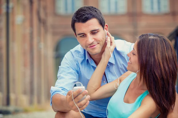 Young brunette couple having fun together with music at park — Stock Photo, Image