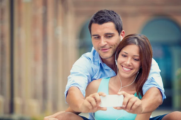 Mladá bruneta pár baví s smartphone v parku — Stock fotografie