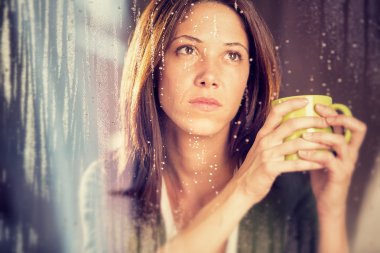 çay ile romantik genç kadın yağmur pencereden bakar