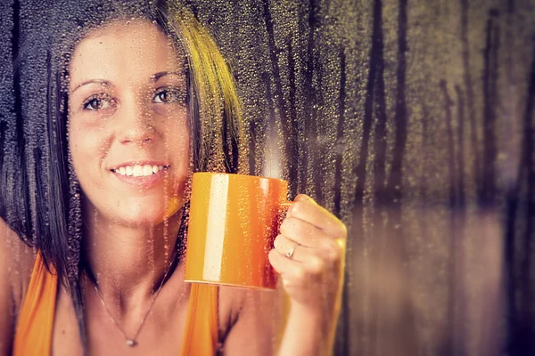 Csésze tea romantikus fiatal nő úgy néz ki, az eső az ablakon — Stock Fotó