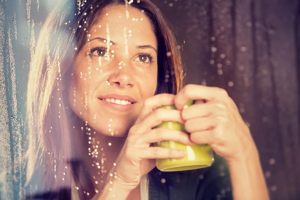 Romantic young woman with cup of tea looks at rain through the window — Stock Photo, Image