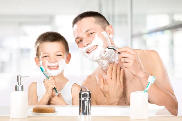 Felice bambino divertirsi con papà con schiuma da barba in bagno — Foto Stock