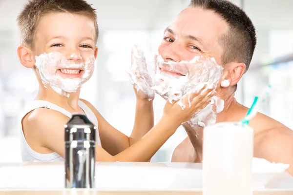 Lyckligt barn ha roligt med pappa med raklödder i badrummet — Stockfoto