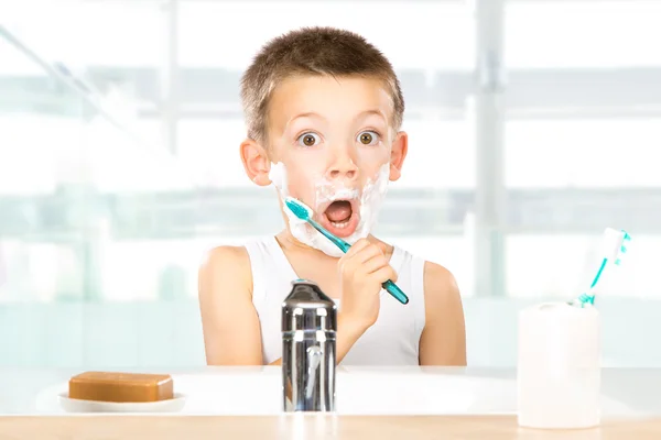 Niño sonriente divertirse con espuma de afeitar en el baño —  Fotos de Stock