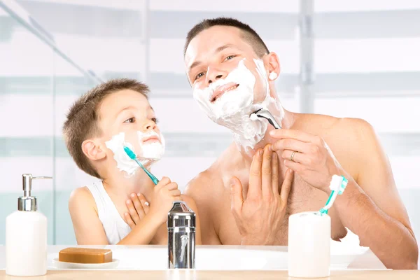Счастливый ребенок развлекается с папой пеной для бритья в ванной — стоковое фото