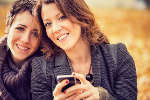 Paar vriendinnen plezier met telefoon in het park — Stockfoto