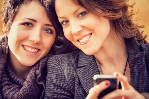 Couple of girl Friends having fun with phone at the park — Stock Photo, Image