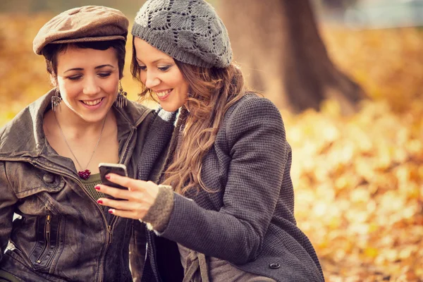 Couple of girl Friends having fun with phone at the park — Stock Photo, Image