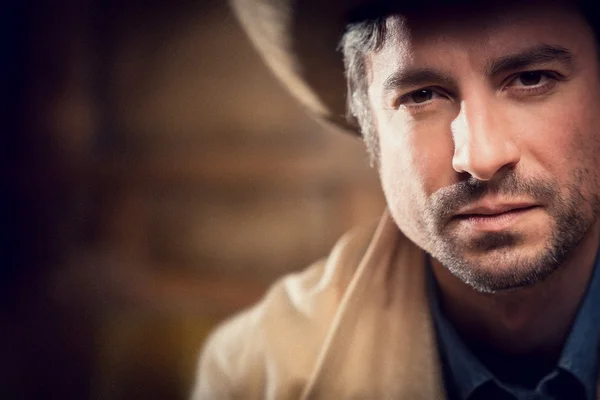 Knappe cowboy met sensuele blik en hoed in een oud huis — Stockfoto