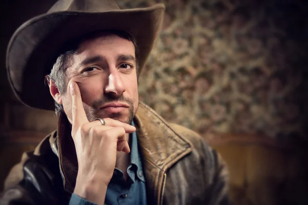 handsome cowboy with sensual gaze and hat in a old house