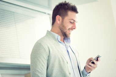 gülümseyen genç casual işadamı ofisinde telefonda konuşuyor