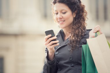 cityscape telefon ile gülümseyen kıvırcık kadın alışveriş