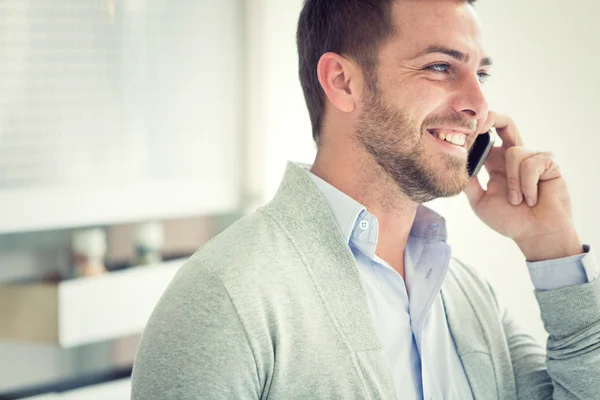 Smiling young casual businessman talking on the phone at office — Stock Photo, Image