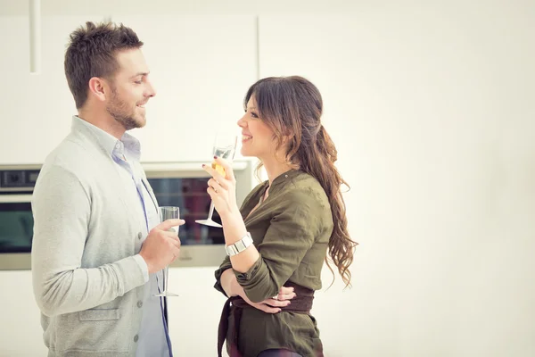 Молода випадкова пара вболіває з шампанським і телефоном на кухні — стокове фото