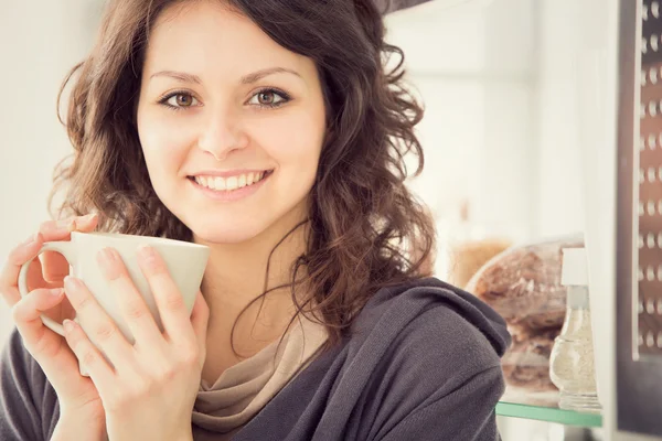 キッチンで紅茶のカップと笑顔の若い女性 — ストック写真