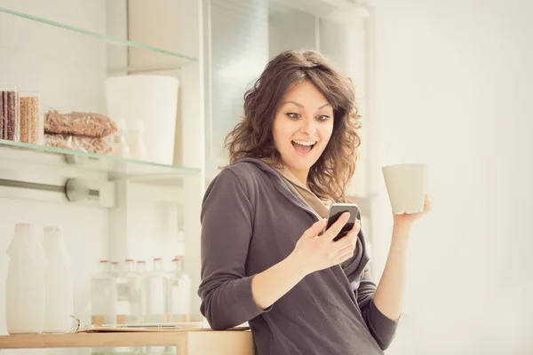 Joven mujer sonriente con taza de té en la cocina — Foto de Stock