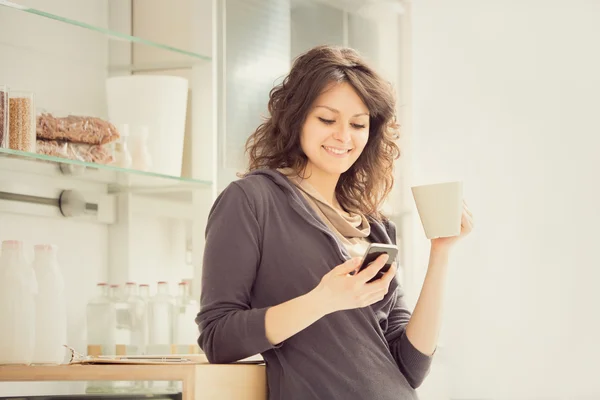 Joven mujer sonriente con taza de té en la cocina — Foto de Stock