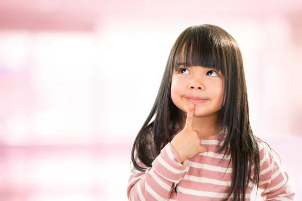 Asiático sorrindo pouco pensativo menina isolado no rosa — Fotografia de Stock