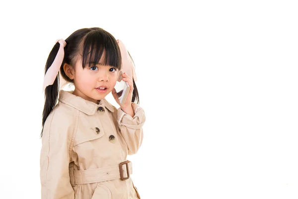 Азіатська усміхнена маленька дівчинка говорить по телефону ізольовано на білому — стокове фото