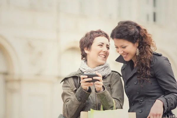 Пара жінок магазин разом з телефоном в міському пейзажі — стокове фото