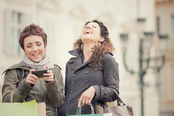 Pareja de mujeres de compras junto con el teléfono en el paisaje urbano — Foto de Stock