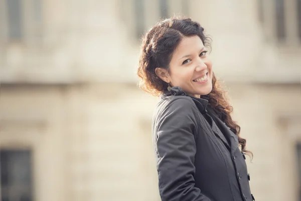 Sonriente mujer rizada en paisaje urbano — Foto de Stock