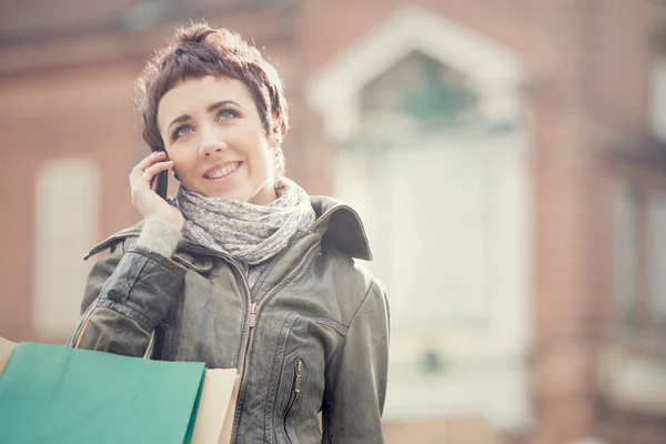 Коротке волосся усміхнена жінка магазин з телефоном в міському пейзажі — стокове фото