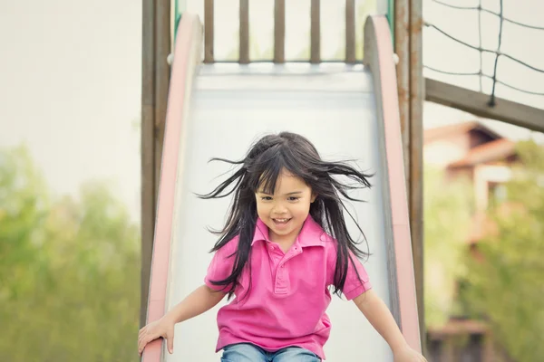 Happy asian smiling child play with slide in a park — Stock Photo, Image